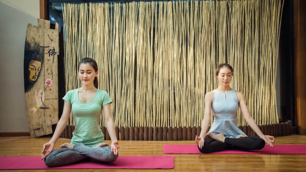 Dos chicas practicando yoga en un estudio bien organizado